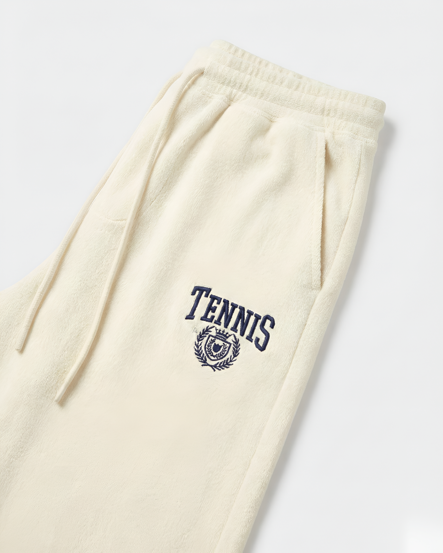 Beige sweatpants with 'Tennis' and crest design on a white background